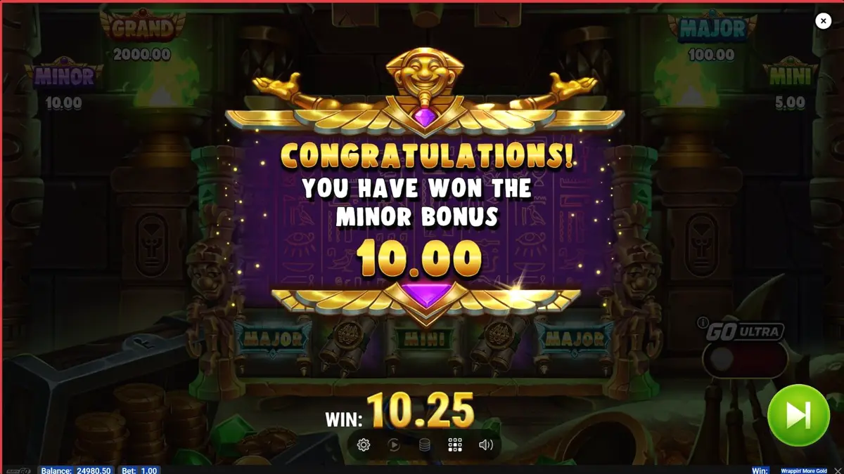 Tampilan antarmuka slot Wrappin’ More Gold dengan mumi ramah dan latar belakang Mesir Kuno